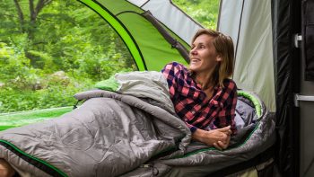 woman laying on side in sleeping bag in GO camping trailer
